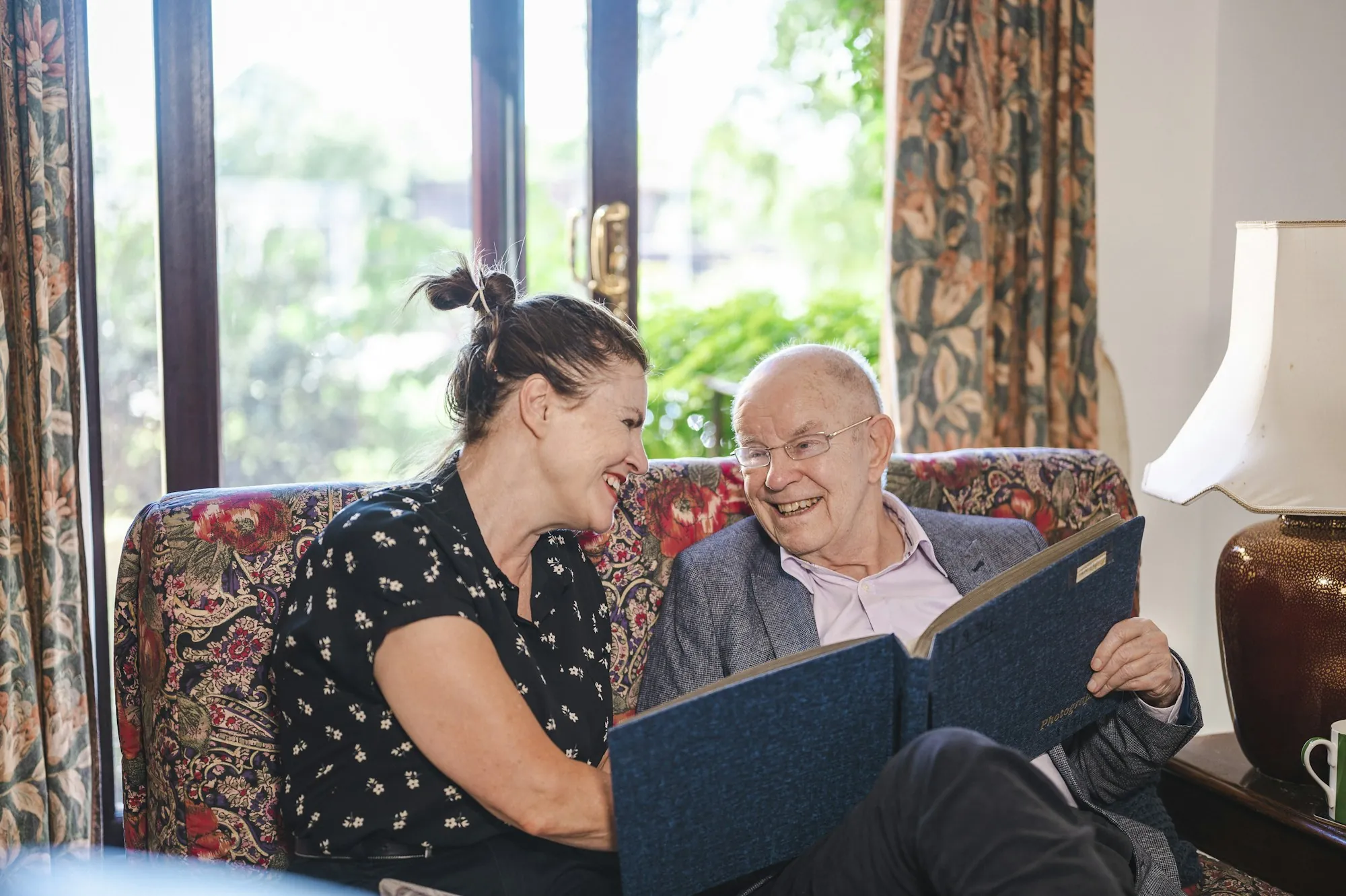 An older man and a visitor sitting together on a couch