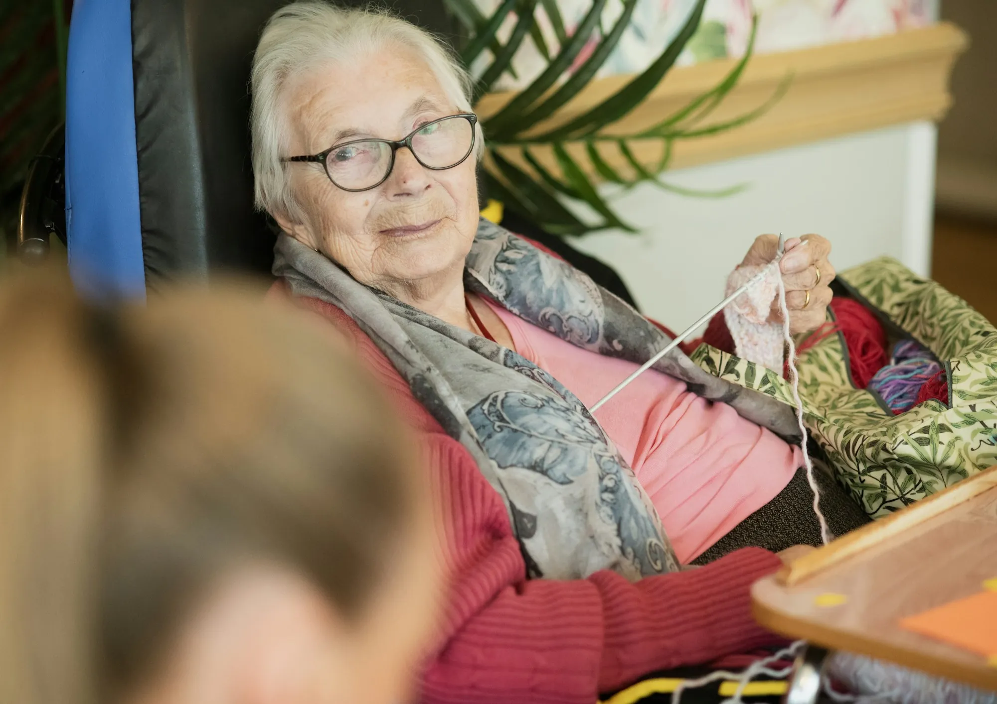An older woman knitting quietly in her own front room