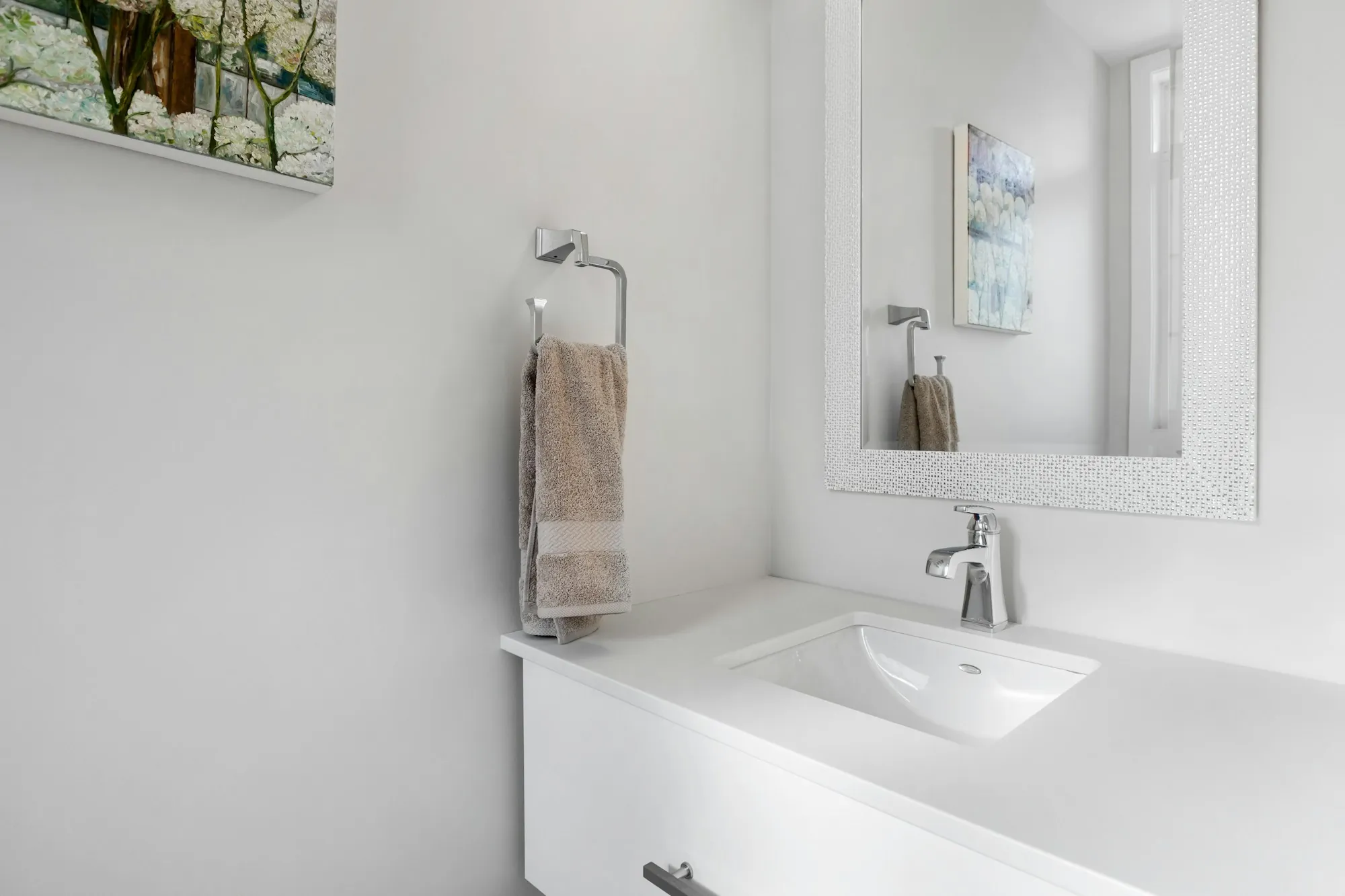 A clean bathroom with a basin, mirror and folded towel