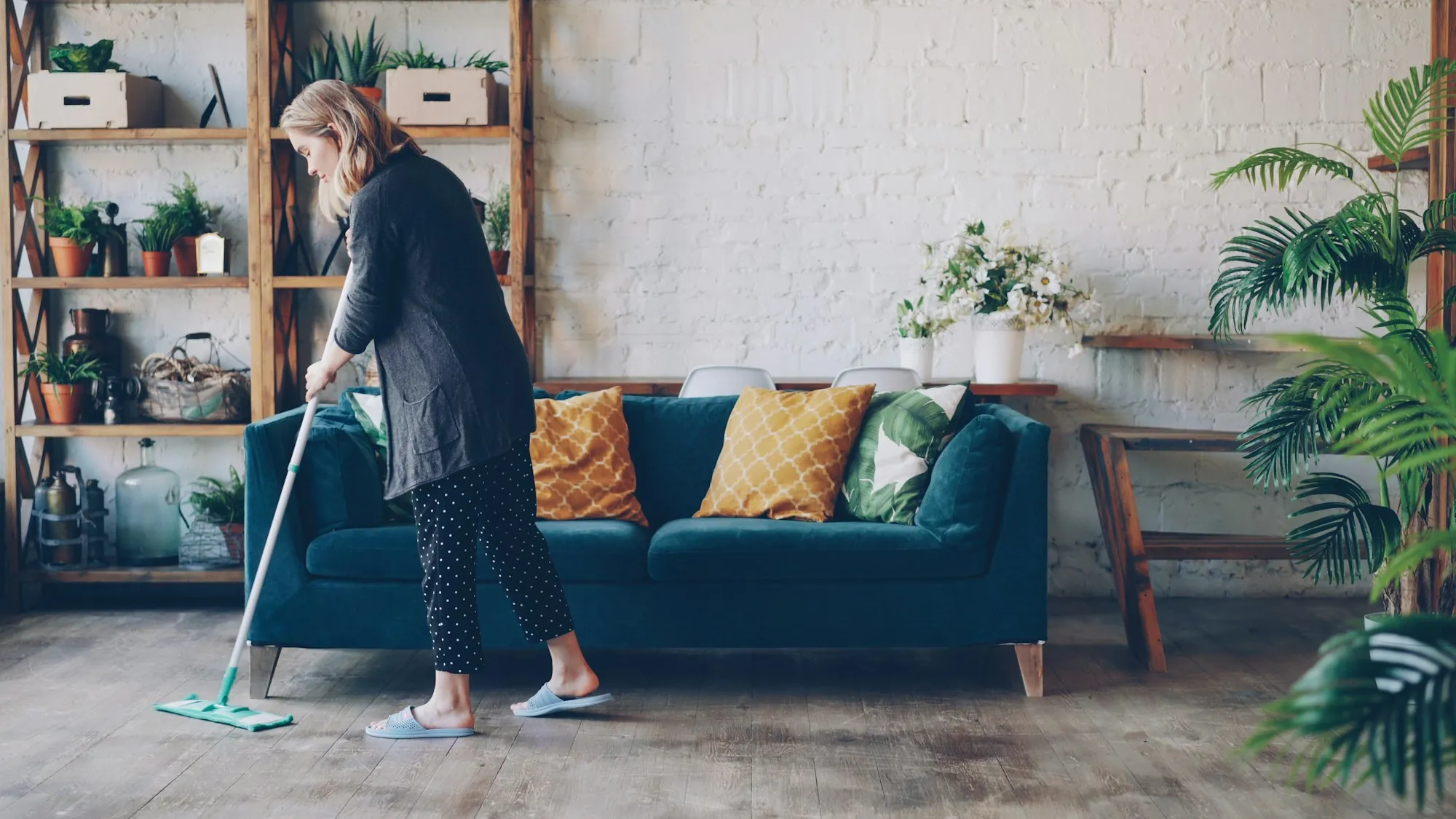 A woman mopping the floor in a bright living room