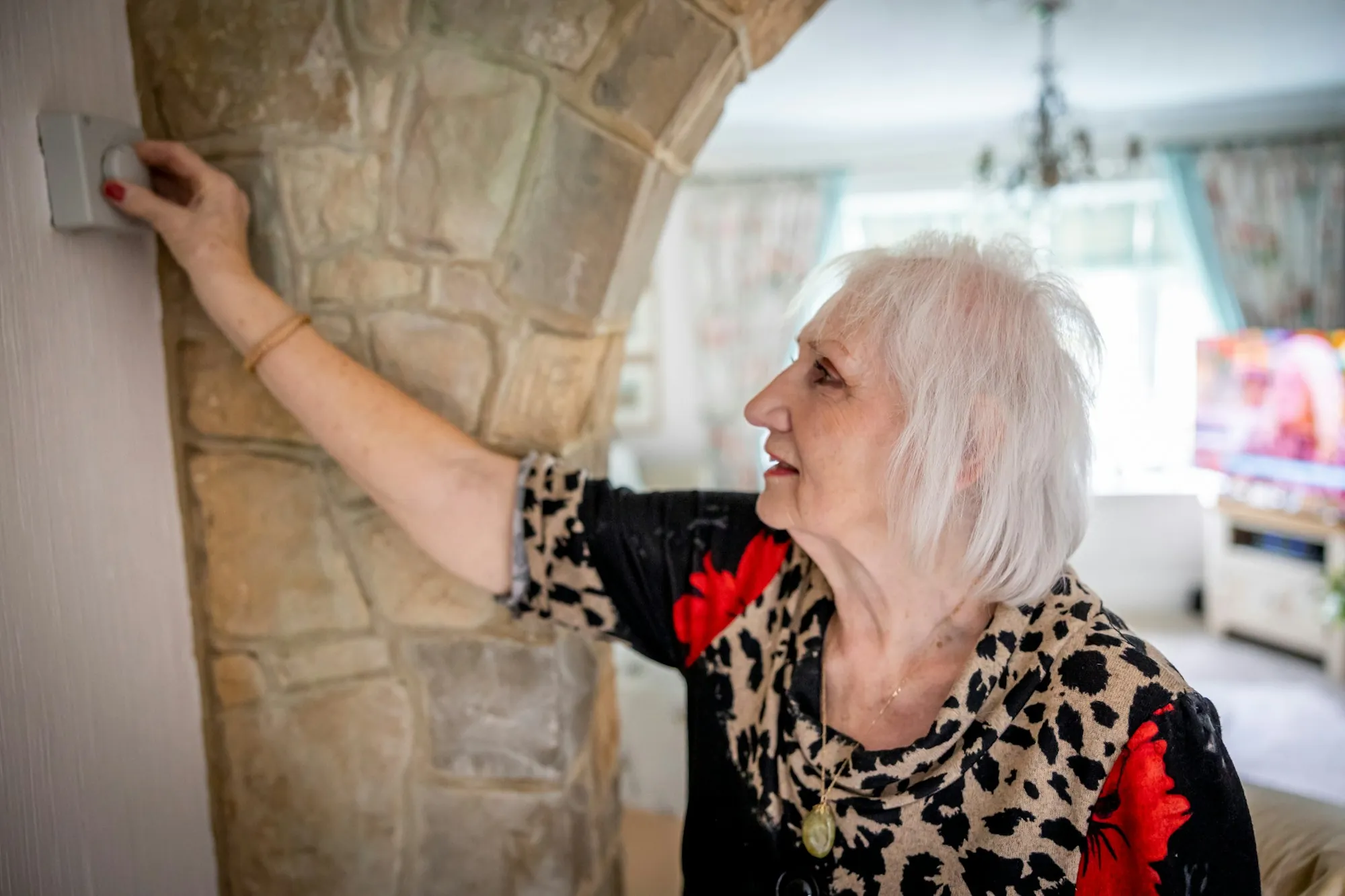 An older woman reaching to switch on a hallway light