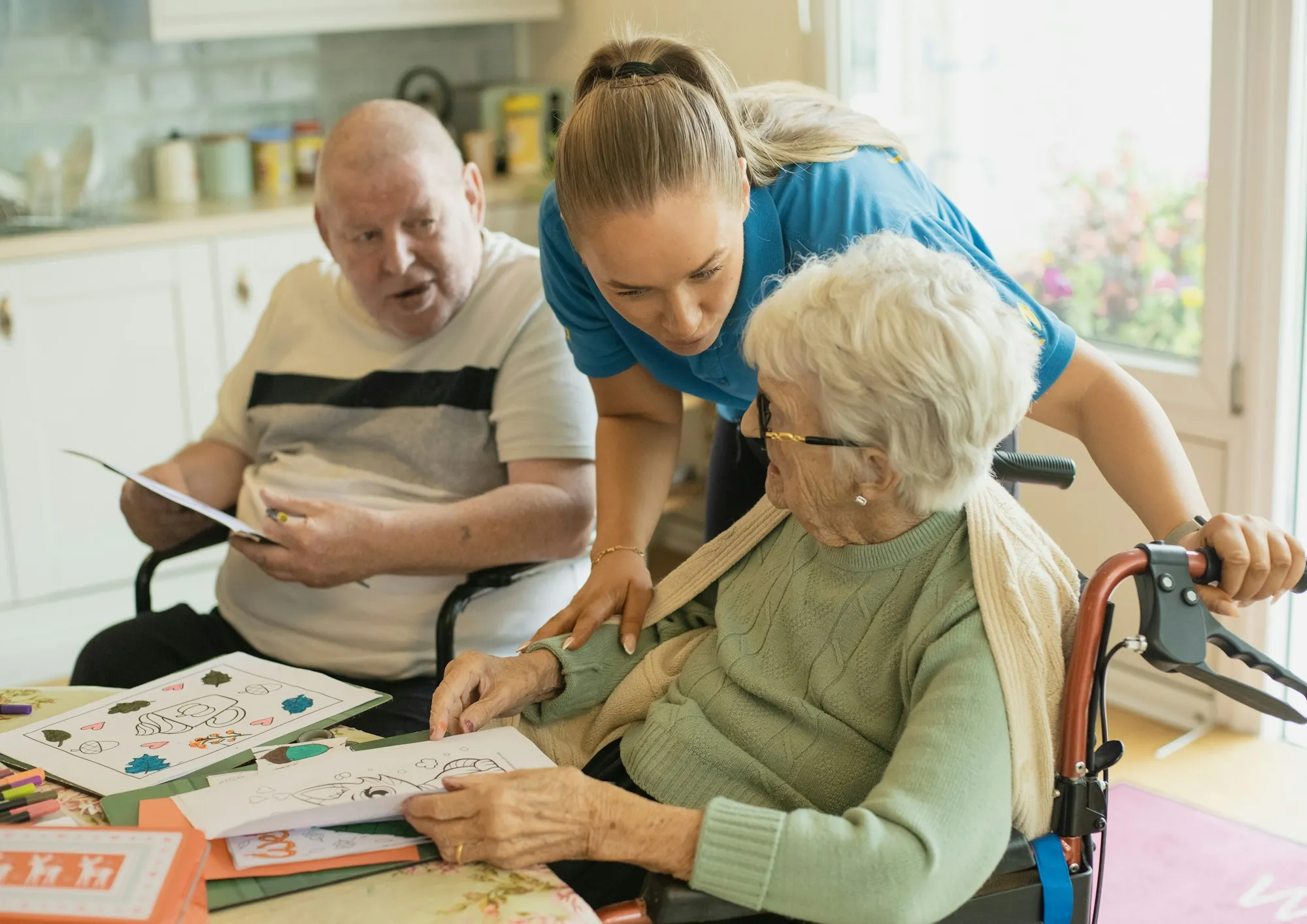 A care worker helping two older people with an activity at a table